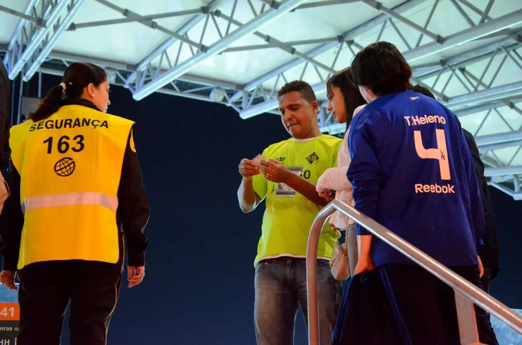 Imagem de seguranças conferindo ingressos de visitantes.